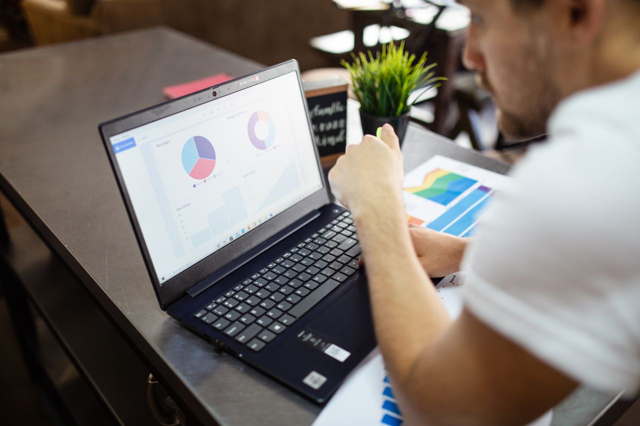 Man reviewing charts and graphs on a laptop for business analysis.